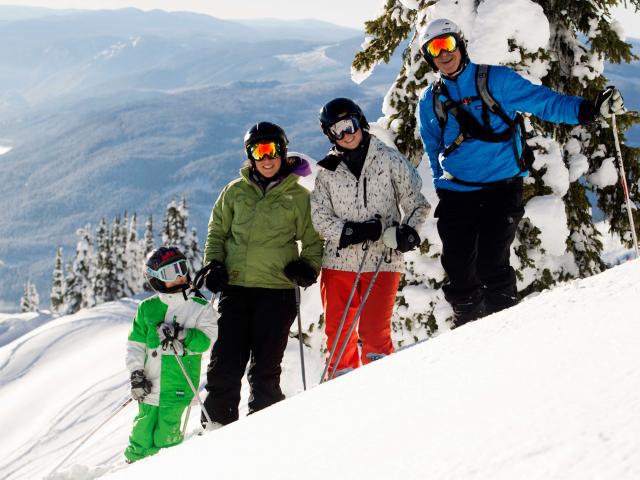 Family powder skiing and snowboarding at Mike Wiegele Heli-skiing in Blue River, BC, Canada.
